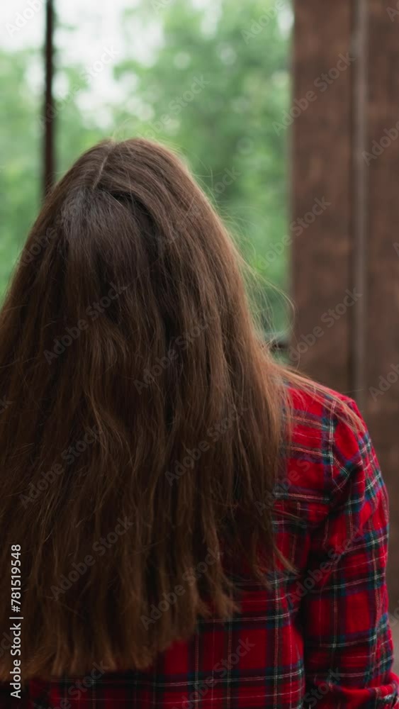 Woman walks tilting head back along terrace. Lady with long red hair wearing checkered shirt rests in studio with panoramic windows. Luxury house Woman walks tilting head back along terrace. Lady with long red hair wearing checkered shirt rests in studio with panoramic windows. Luxury house