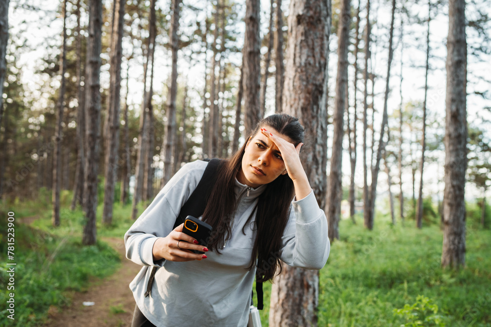 One young caucasian woman is hiking through the forest and looking for the way One young caucasian woman is hiking through the forest and looking for the way
