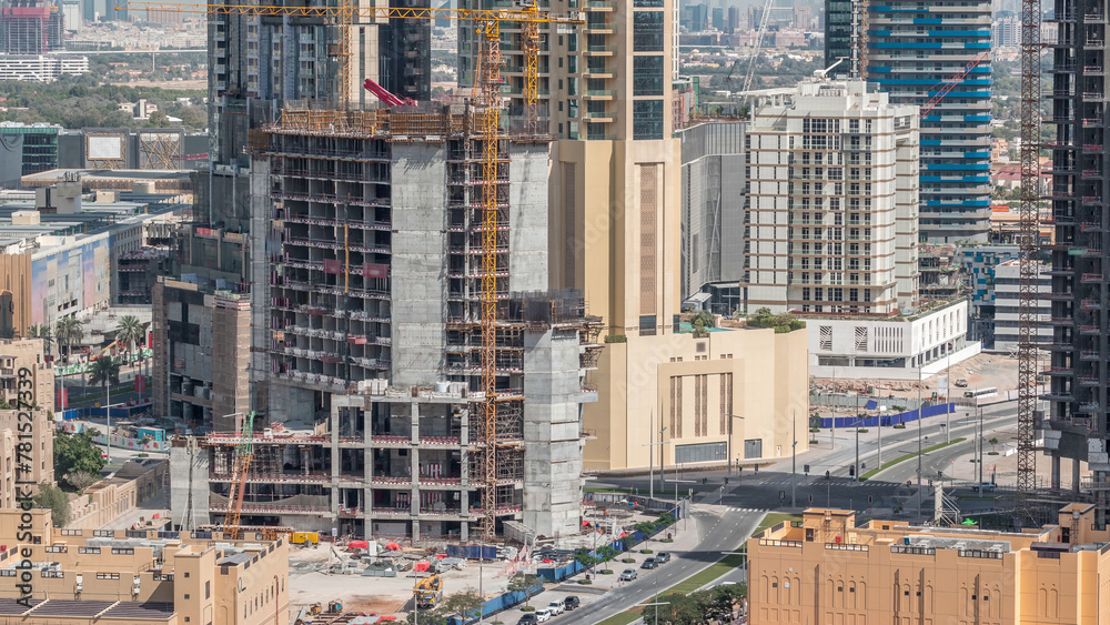 Fototapeta premium Aerial view of a skyscraper under construction with huge cranes in Dubai timelapse. United Arab Emirates