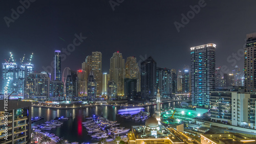 Yachts in Dubai Marina flanked by the Al Rahim Mosque and residential towers and skyscrapers aerial night timelapse. © neiezhmakov