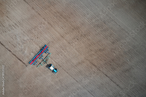 Sowing campaign. Aerial view of a tractor with a planter on arable land. Wheat seeds and mineral fertilizer in the planter compartments. Copy space. photo