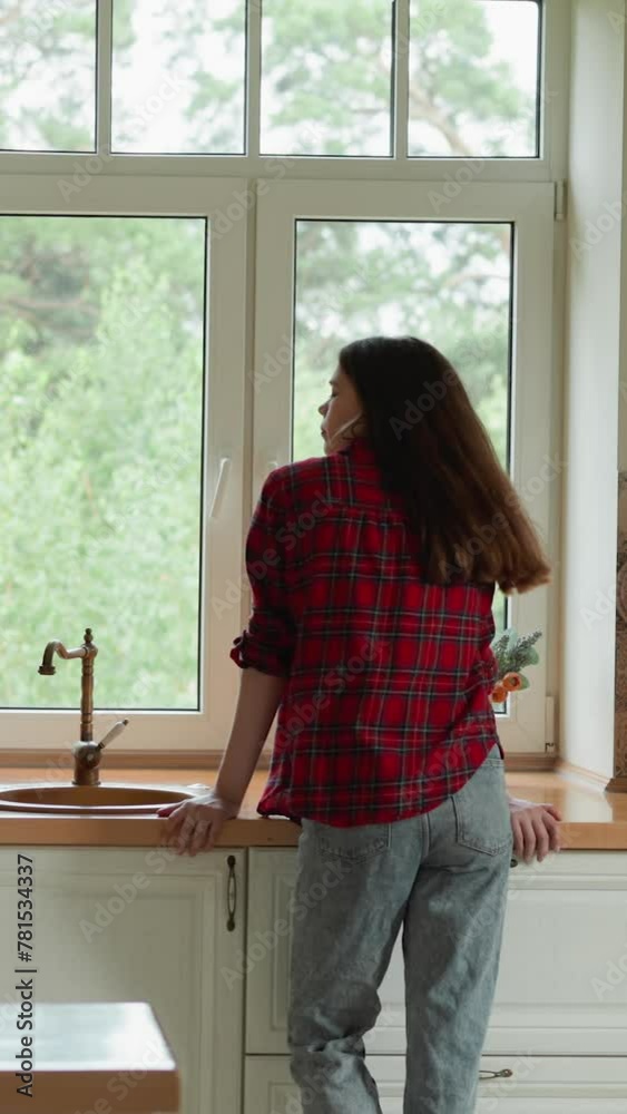 Broken woman leans on countertop in kitchen. Sorrowful lady shakes hair and bend head down by window. Wife offended by husband cheating and lie Broken woman leans on countertop in kitchen. Sorrowful lady shakes hair and bend head down by window. Wife offended by husband cheating and lie