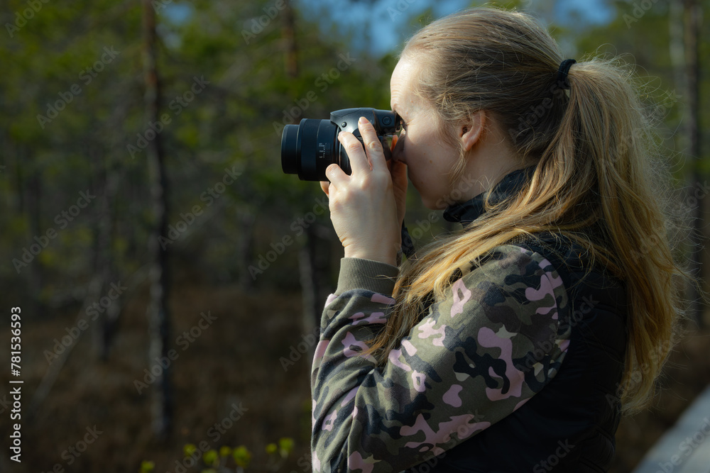 A woman with a camera takes pictures of pines in a natural swamp A woman with a camera takes pictures of pines in a natural swamp