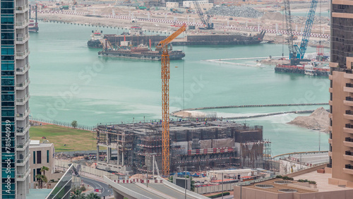 Aerial view of a skyscraper under construction with huge cranes timelapse in Dubai marina. photo