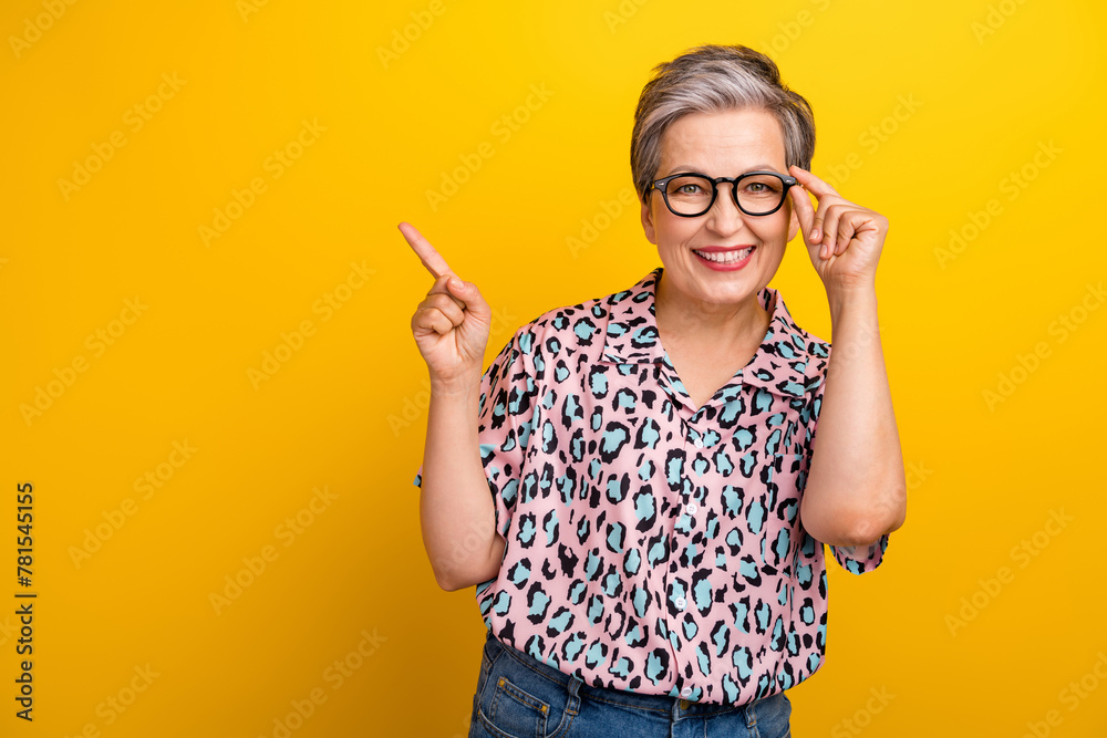 Photo portrait of pretty retired female point empty space poster dressed stylish leopard print outfit isolated on yellow color background - obrazy, fototapety, plakaty 
