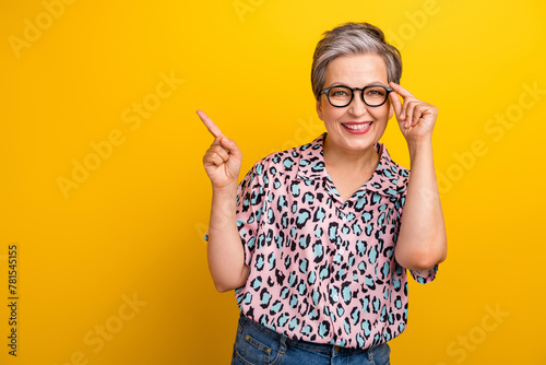 Photo portrait of pretty retired female point empty space poster dressed stylish leopard print outfit isolated on yellow color background