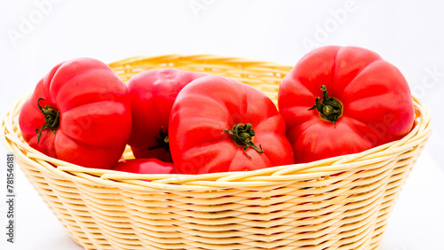 Fresh and tasty red tomatoes in wicker basket isolated