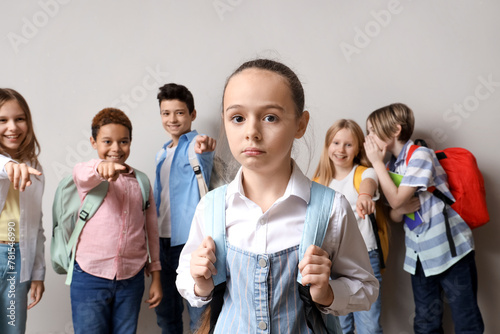 Bullied little girl and her classmates on light background © Pixel-Shot