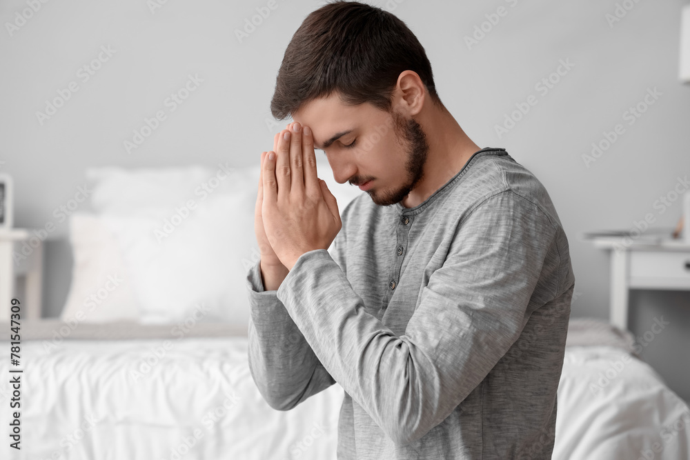 Young man praying in bedroom Young man praying in bedroom