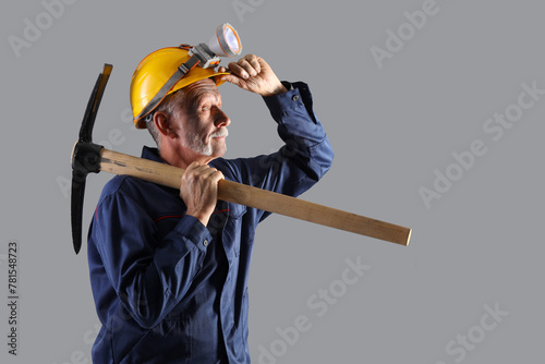 Mature miner man with pick axe on grey background photo