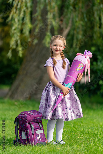 blondes glückliches stolzes sechsjähriges Mädchen mit Schultüte und Schulrucksack, erstklässlerin, sonniger tag, schulanfang