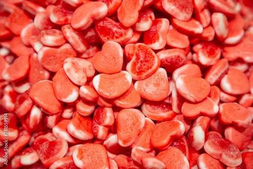 Candy background, chewing jelly candies in the form of red hearts, top view.