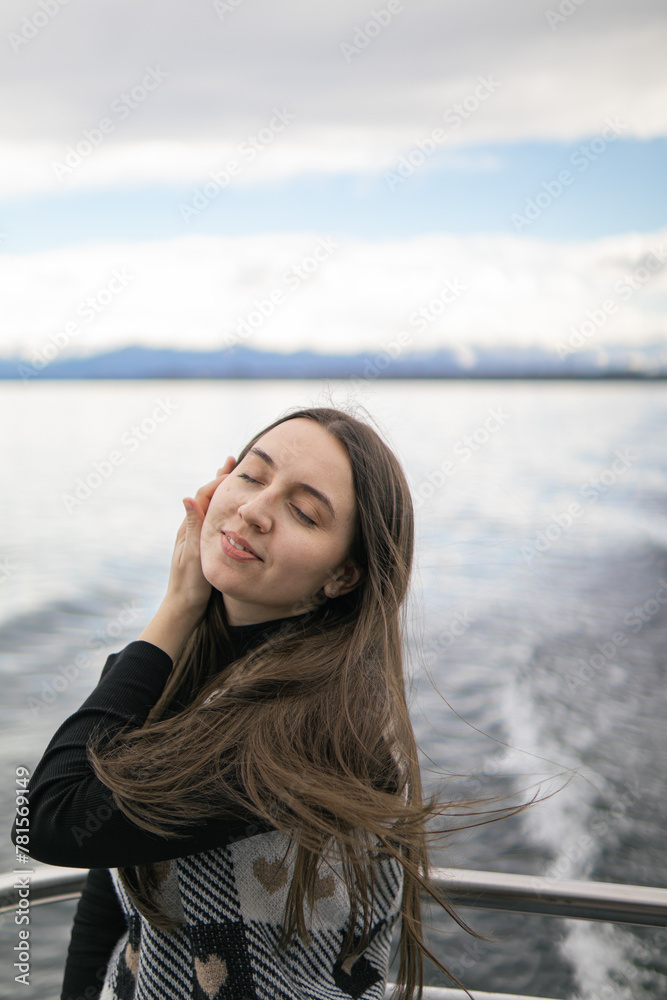 a pensive dreamy young woman sails on a ship on an alpine lake against the backdrop of mountains.beautiful brunette is sad and dreams, enjoying nature. a pensive dreamy young woman sails on a ship on an alpine lake against the backdrop of mountains.beautiful brunette is sad and dreams, enjoying nature.