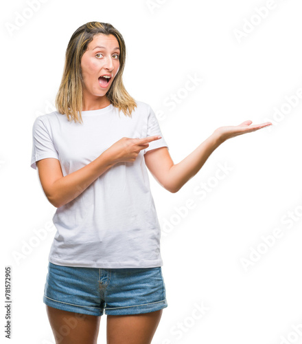 Young beautiful woman over isolated background amazed and smiling to the camera while presenting with hand and pointing with finger.