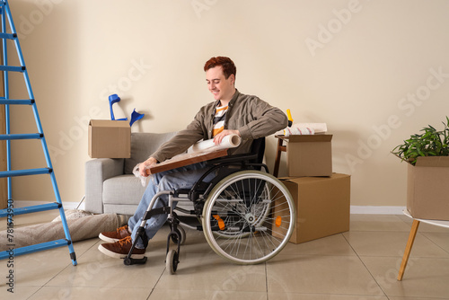 Young man in wheelchair wrapping painting during repair at home