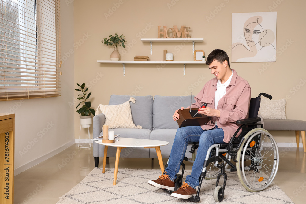 Young man in wheelchair repairing radio receiver at home Young man in wheelchair repairing radio receiver at home