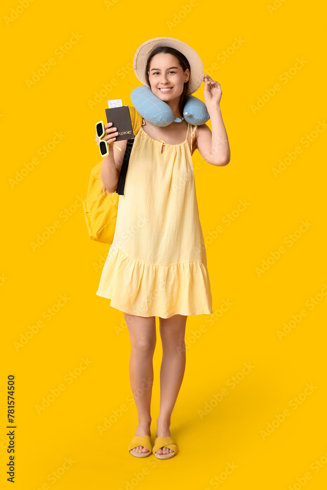 Fototapeta premium Young happy woman in hat with passport and backpack on yellow background. Travel concept