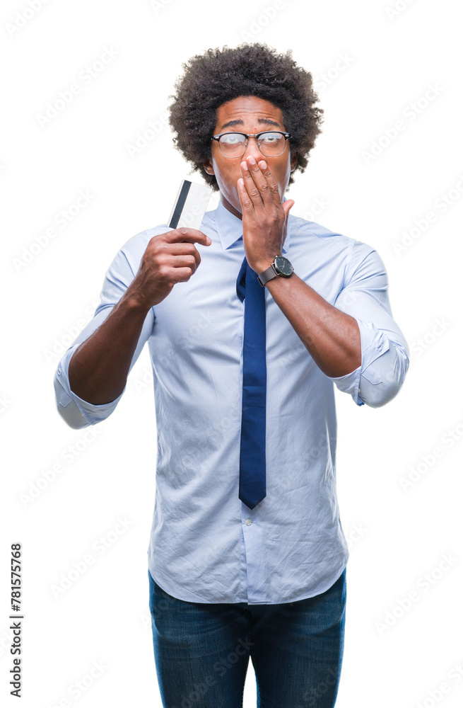 Afro american man holding credit card over isolated background cover mouth with hand shocked with shame for mistake, expression of fear, scared in silence, secret concept Afro american man holding credit card over isolated background cover mouth with hand shocked with shame for mistake, expression of fear, scared in silence, secret concept