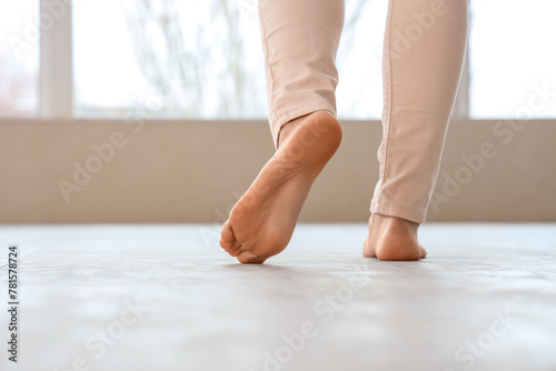 Young woman walking on new laminate flooring at home, back view