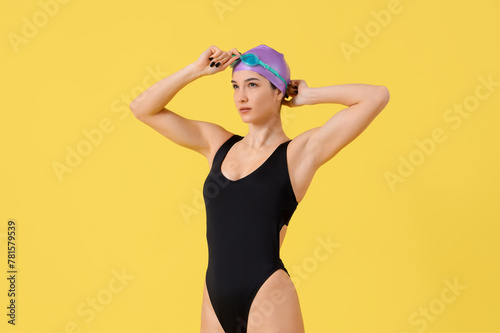 Young female swimmer on yel...
