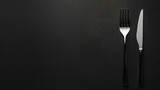 Fork and knife set on a dark background, epitomising minimalist elegance.