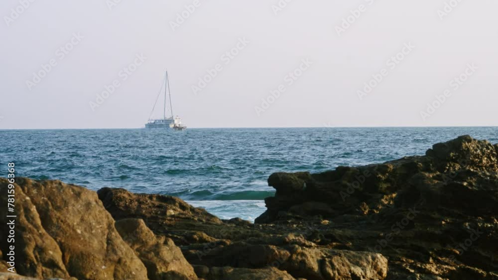 Sailboat navigates vast blue ocean, white sails against clear sky. Waves crash on rocky shore, hint at sea untamed nature. Yacht journey. Perfect day for sailing, clear horizon promises travels. Slomo Sailboat navigates vast blue ocean, white sails against clear sky. Waves crash on rocky shore, hint at sea untamed nature. Yacht journey. Perfect day for sailing, clear horizon promises travels. Slomo