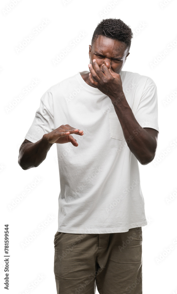 Young african american man wearing white t-shirt smelling something stinky and disgusting, intolerable smell, holding breath with fingers on nose. Bad smells concept. Young african american man wearing white t-shirt smelling something stinky and disgusting, intolerable smell, holding breath with fingers on nose. Bad smells concept.