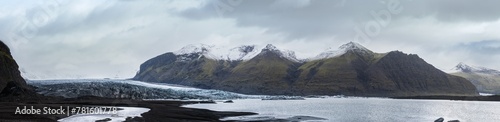 Skaftafellsjokull glacier, Iceland. Glacier tongue slides from the Vatnajokull icecap or Vatna Glacier near subglacial Esjufjoll volcano. Glacial lagoon with ice blocks and surrounding mountains. photo