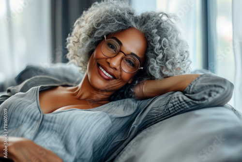 Close up satisfied calm african woman put hands behind head resting daydreaming on sofa, black attractive 60s female spend time at home closed eyes relaxing feels serenity no stress enjoy lazy weekend photo