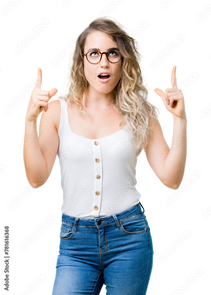 Beautiful young blonde woman wearing glasses over isolated background amazed and surprised looking up and pointing with fingers and raised arms. Beautiful young blonde woman wearing glasses over isolated background amazed and surprised looking up and pointing with fingers and raised arms.