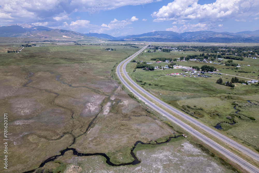 Open Road Bending through Vast Green Fields and Distant Mountains