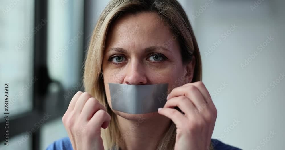 Woman covers mouth with tape and gestures silence Woman covers mouth with tape and gestures silence