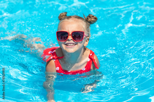 Child in swimming pool. Tropical vacation for family with kids. Little girl wearing red swimsuit playing in outdoor pool of exotic island resort. Water and swim fun for children