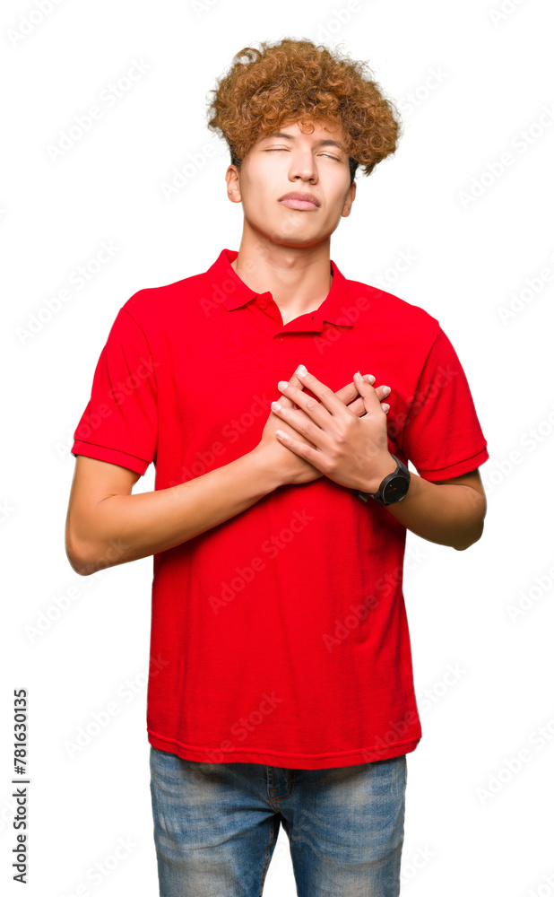 Young handsome man with afro hair wearing red t-shirt smiling with hands on chest with closed eyes and grateful gesture on face. Health concept. Young handsome man with afro hair wearing red t-shirt smiling with hands on chest with closed eyes and grateful gesture on face. Health concept.