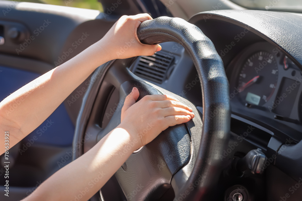 Hands on the steering wheel. The boy holds the steering wheel of the car. Selective focus