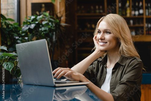 Young businesswoman student freelancer self-employed female working remotely on distance on laptop, e-learning, watching tutorials, webinars online in cafe restaurant bar counter
