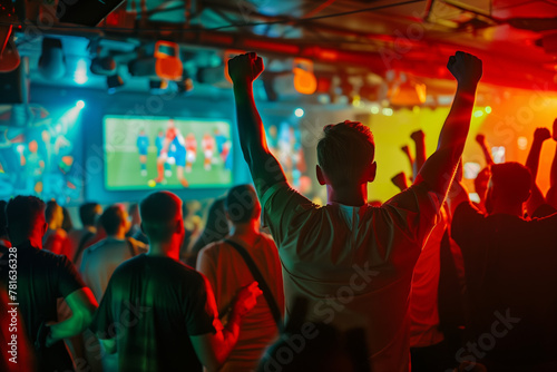 A silhouette of an elated sports fan is captured against the vibrant backdrop of a bar's televised sports event. 