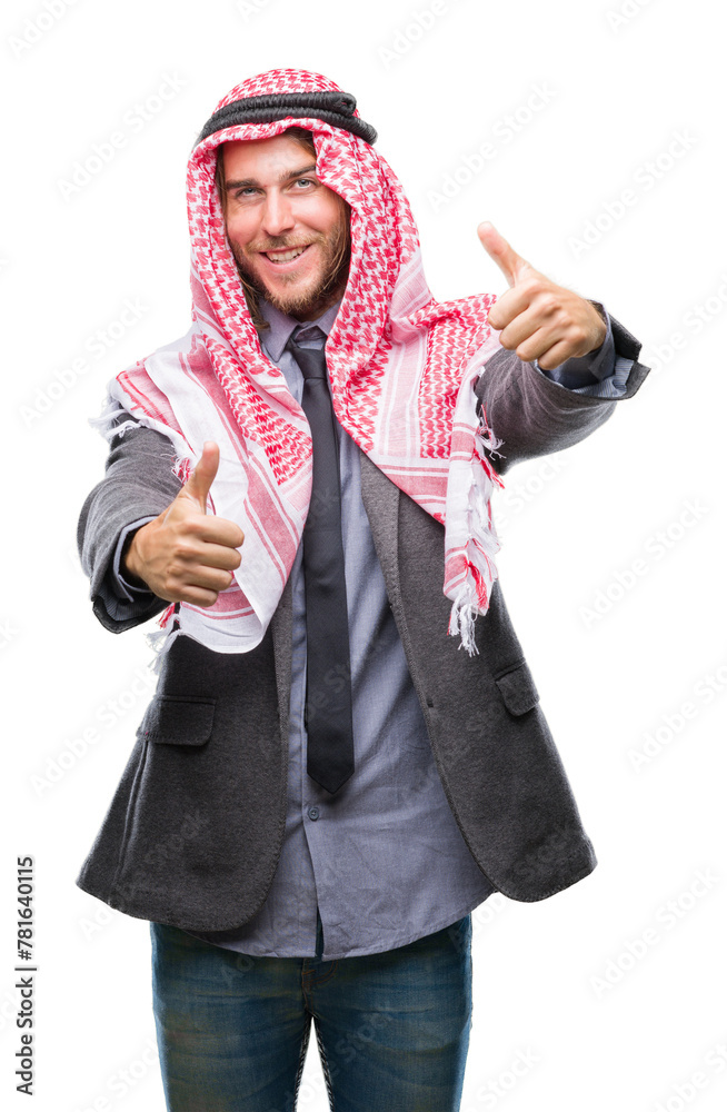 Young handsome arabian man with long hair wearing keffiyeh over isolated background approving doing positive gesture with hand, thumbs up smiling and happy for success. Looking at the camera Young handsome arabian man with long hair wearing keffiyeh over isolated background approving doing positive gesture with hand, thumbs up smiling and happy for success. Looking at the camera