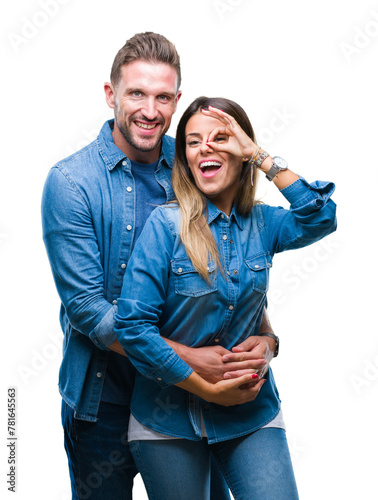Young couple in love over isolated background doing ok gesture with hand smiling, eye looking through fingers with happy face.