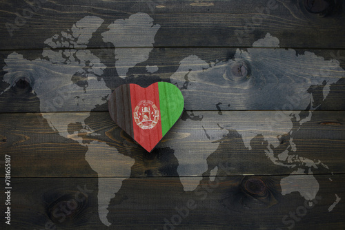 wooden heart with national flag of afghanistan near world map on the wooden background.
