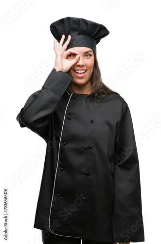 Young hispanic cook woman wearing chef uniform with happy face smiling doing ok sign with hand on eye looking through fingers