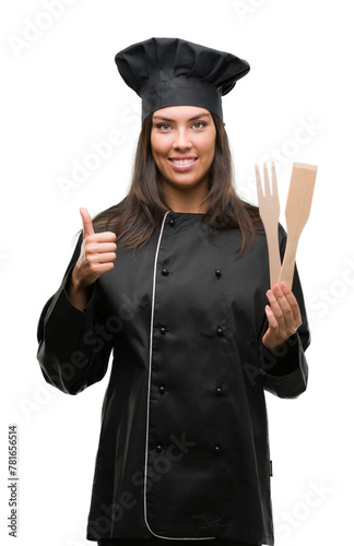Young hispanic cook woman wearing chef uniform happy with big smile doing ok sign, thumb up with fingers, excellent sign