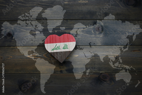 wooden heart with national flag of iraq near world map on the wooden background.