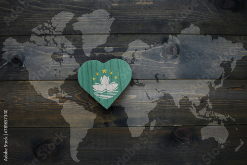 wooden heart with national flag of Macau near world map on the wooden background.
