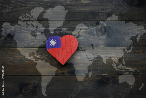 wooden heart with national flag of taiwan near world map on the wooden background. photo