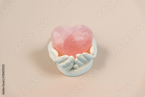 Gypsum hands holding a crystal stone heart (light brown background)