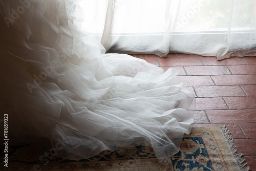 bridal gown train elegantly draped over vintage rug near window