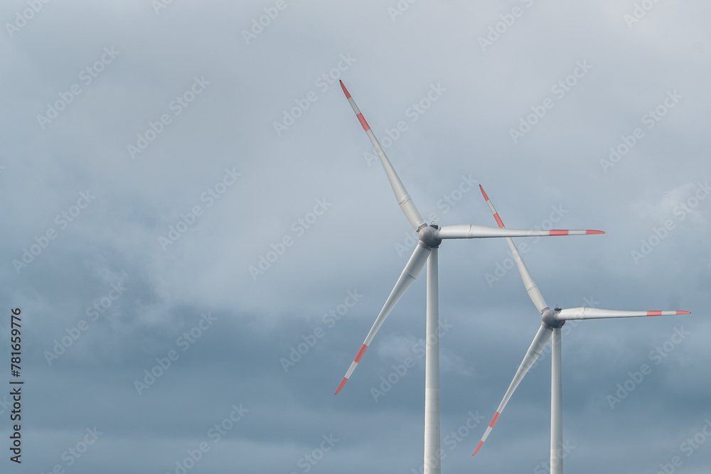 Two synchronous wind turbines under the cloudy sky Two synchronous wind turbines under the cloudy sky