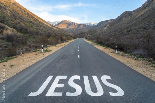 Asphalt road surrounded by mountains, Jesus written on the road. Christian concept. Jesus is the way