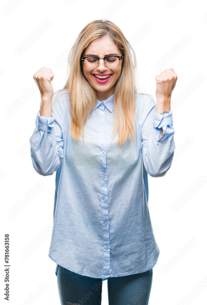 Young beautiful blonde business woman wearing glasses over isolated background excited for success with arms raised celebrating victory smiling. Winner concept. Young beautiful blonde business woman wearing glasses over isolated background excited for success with arms raised celebrating victory smiling. Winner concept.
